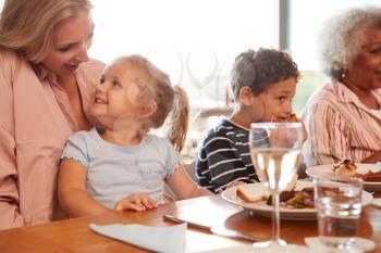 Multi-Generation Family Sitting Around Table Enjoying Meal At Home Together
