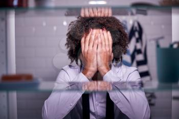 View Through Bathroom Cabinet Of Unhappy Businessman Covering Face With Hands