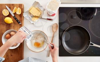 Overhead Shot Of Woman In Kitchen Mixing Ingredients For Pancakes Or Crepes For Pancake Day