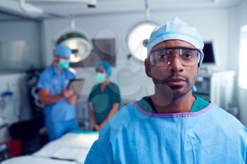 Portrait Of Male Surgeon Wearing Scrubs And Protective Glasses In Hospital Operating Theater