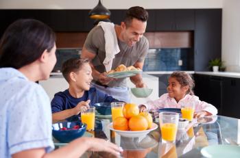 Hispanic Family Sitting Around Table Eating Breakfast Together
