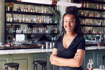 Portrait Of Confident Female Owner Of Restaurant Bar Standing By Counter