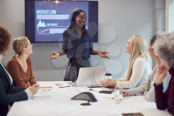 Young Businesswoman Leading Creative Meeting Of Women Collaborating Around Table In Modern Office