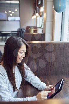 Young Asian Businesswoman Using Digital Tablet In Break Out Area Of Modern Office