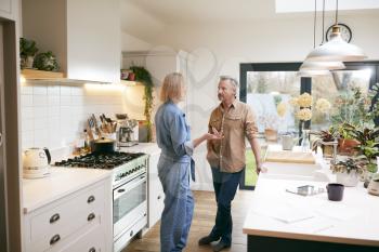 Mature Couple Having Discussion In Kitchen At Home Together