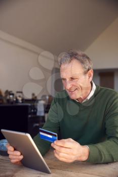 Senior Man At Home Buying Products Or Services Online Using Digital Tablet And Credit Card
