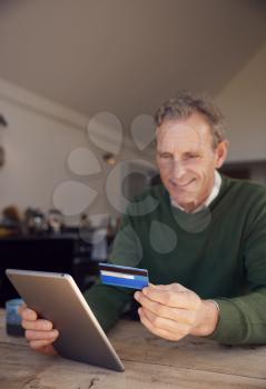 Senior Man At Home Buying Products Or Services Online Using Digital Tablet And Credit Card