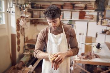 Male Potter Cleaning Hands With Sponge In Ceramics Studio
