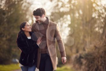 Loving Young Couple Walking Through Winter Countryside Together