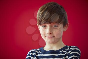 Portrait Of Young Boy Against Red Studio Background Smiling At Camera