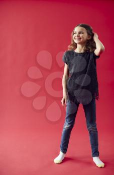 Full Length Portrait Of Girl Against Red Studio Background Smiling At Camera