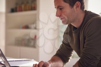 Man With Laptop Working From Home On Kitchen Counter