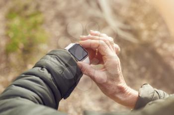 Close Up Of Senior Woman Running In Countryside Exercising Checking Smart Watch Fitness Activity App