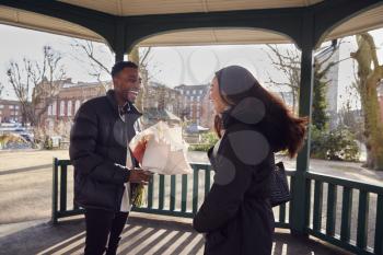Romantic Man Surprising Young Woman With Bouquet Of Flowers As They Meet In City Park