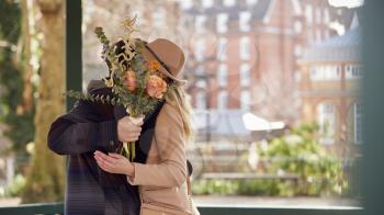 Romantic Man Hugging Young Woman With Faces Hidden Behind A Bouquet Of Flowers He Gives Her