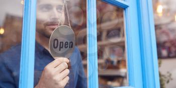 Small Business Owner Turning Around Open Sign On Shop Or Store Door