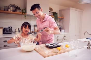 Asian Father And Daughter Making Cupcakes In Kitchen At Home Together