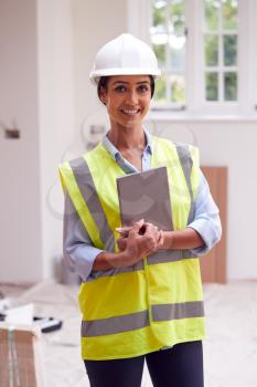 Portrait Of Female Building Surveyor Wearing Hard Hat With Digital Tablet Looking At New Property