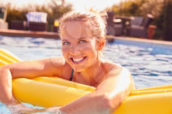 Portrait Of Woman Having Fun With Inflatable On Summer Vacation In Outdoor Swimming Pool