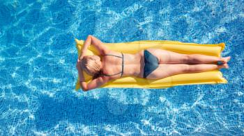 Overhead Shot Of Woman In Bikini Floating On Air Bed On Summer Vacation In Outdoor Swimming Pool
