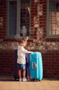 Young Boy With Suitcase Outside House Preparing To Leave For Family Vacation