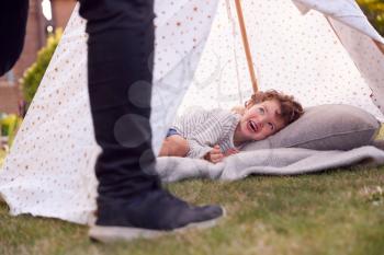 Close Up Of Father And Son Having Fun With Tent Or Tepee Pitched In Garden