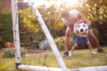 Father With Son Having Fun In Park Or Garden Playing Soccer Together