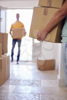 Close Up Of Couple Carrying Boxes Through Front Door Of New Home On Moving Day