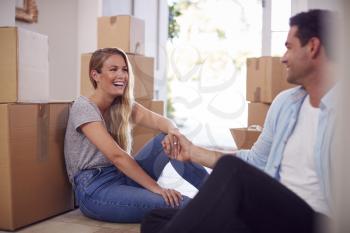 Loving Couple Taking A Break Sitting On Floor Of New Home On Moving Day