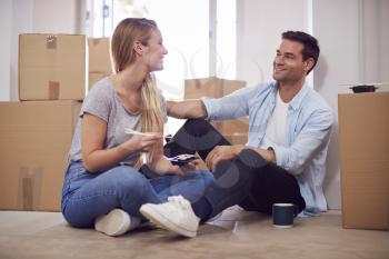 Couple Celebrating With Takeaway Sushi Meal Sitting On Floor Of New Home On Moving Day