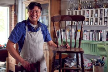 Portrait Of Mature Asian Man Restoring Furniture In Workshop At Home