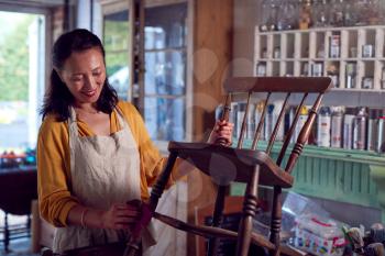Mature Asian Woman Restoring Furniture In Workshop At Home