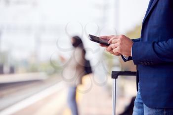 Close Up Of Businessman On Railway Platform Texting On Mobile Phone