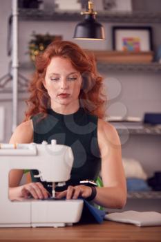 Female Student Or Business Owner Working In Fashion Using Sewing Machine In Studio