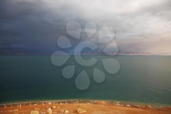 Winter on the Dead Sea. Blue storm cloud, green water and magnificent rainbow