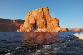Travel voyage by boat on Lake Powell. Picturesque waves astern the ship. Sunset rays illuminate the rocks on the shore of the lake. Arizona, USA.