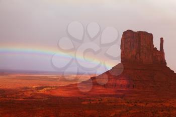 Famous mittens of red sandstone in a fog after the storm and a rainbow in the sky