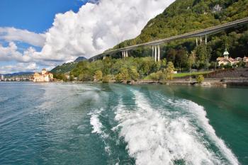  A foamy trace of a walking boat along coast of lake Leman in Switzerland and a motorway on coast