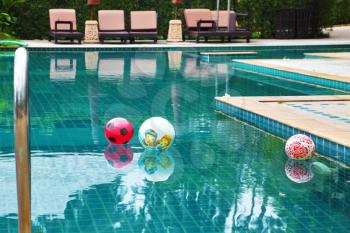 Three beautiful colored balls floating in the clear water of the pool at the hotel. Koh Samui
