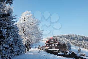 A lovely sunny Christmas Day. Snow-covered slope and a cozy ski hotel
