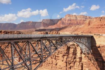 The easy metal bridge through the river Colorado in abrupt coast of desert from red sandstone
