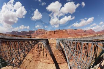The easy metal bridge through the river Colorado in abrupt coast of desert from red sandstone
