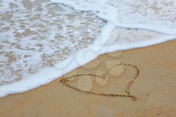 Sandy beach on Koh Samui. In the froth of surf on the sand drawn by heart

