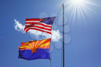 Flags of the United States and the Navajo Reservation are flying against the shining sun