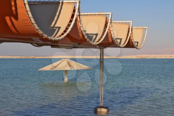 Sunny beach on the Dead Sea. A wonderful warm day in December. The beach pavilion is half flooded with seawater risen