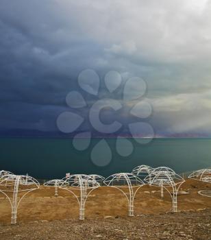 The beach canopies on deserted coast of the Dead Sea in a thunder-storm