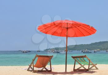  Red beach umbrella and deck chairs on the white sand. Tropical paradise on the shores of the azure sea.