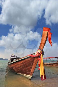 The nose of a boat is decorated by multi-coloured and bright silk scarfs. Orange Thai boat for tourists. 