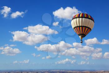 Huge air balloon flying in the cloudy sky above the earth