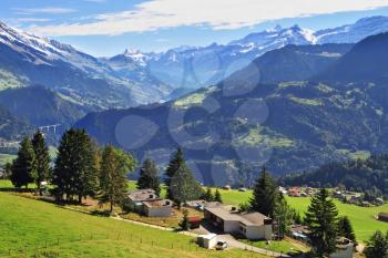Picturesque gentle alpine meadows and rural houses chalets with red roofs. Gorgeous weather in the resort town of Leysin in the Swiss Alps